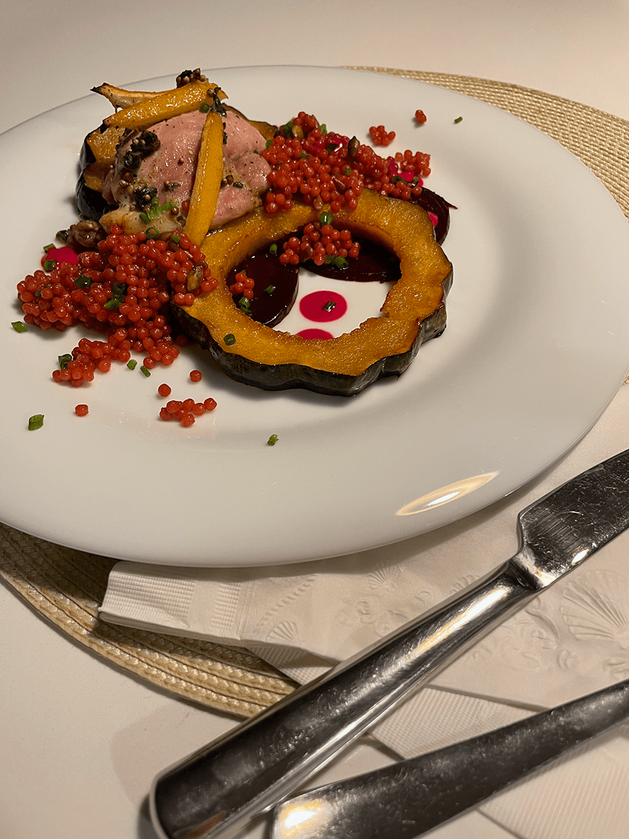 A plated dish — duck with roasted delicata squash and red couscous